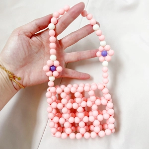Detail of pink beaded mini handbag with handmade floral accents and hollow grid patterns