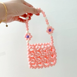 Close-up of handmade beaded handbag with colorful grid pattern and floral charms