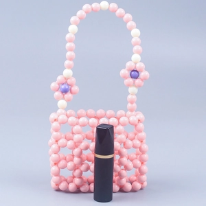 Detail view of pink beaded mini handbag with floral accents and a lipstick for size scale