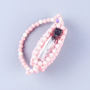 Close-up of handmade pink macaron beaded handbag with floral pattern and perfume prop