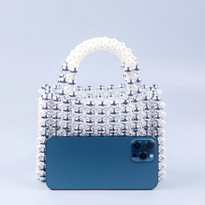 Mini handmade square beaded handbag with silver metallic and white pearls beside a phone