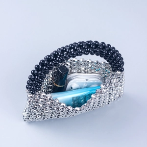 Handmade beaded handbag with silver and black beads showing storage capacity for cosmetics