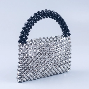 Detail of handcrafted beaded handbag featuring silver acrylic cubes and black handle