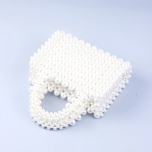 Close-up of the elegant white pearl woven handbag with a round handle and boxy shape