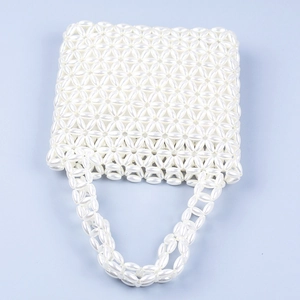 Close-up of white pearl beaded handbag featuring hollow out floral pattern texture