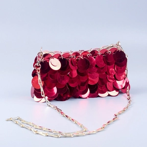 Detailed view of red paillettes on an evening bag with golden chain and metallic texture