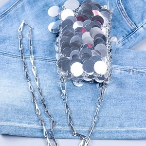 Gros plan détaillé du sac à paillettes argentées avec chaîne sur fond de jean bleu