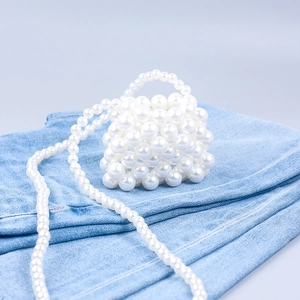 Detailed view of mini white beaded lipstick bag on denim texture for styling