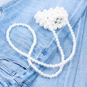 Top view of mini handmade pearl beaded crossbody bag over blue denim texture background