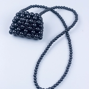 Detailed view of handmade black beaded mini bag with glossy finish and long strap