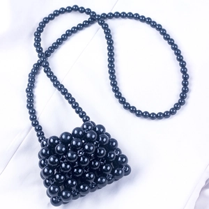 Macro shot of handmade black beaded mini bag with shiny texture on white silk fabric