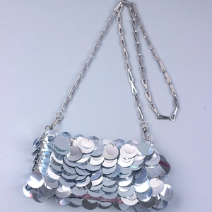 Macro shot of layered silver sequins and metallic chain on a stylish evening bag