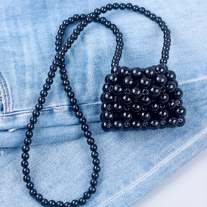 Detailed view of handmade black beaded mini bag on denim fabric background