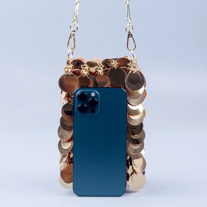 Détail du mini sac à paillettes dorées montrant la taille par rapport au smartphone