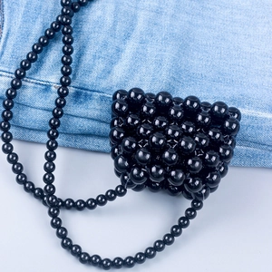Close-up of handmade black beaded mini crossbody bag with glossy woven resin beads