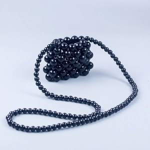 Detail of a handmade black beaded mini crossbody bag with glossy textured beads
