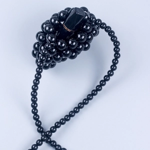 Close-up of handmade black beaded mini lipstick bag with intricate woven texture