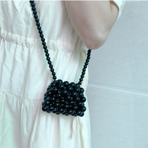 Detail of a handmade mini black beaded crossbody bag with a slim strap for lipstick