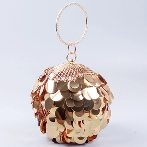 Detail of golden spherical evening bag featuring large sequins and rhinestone metal ring handle