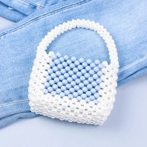 Handmade blue and white acrylic beaded handbag on denim, stylish summer woven tote