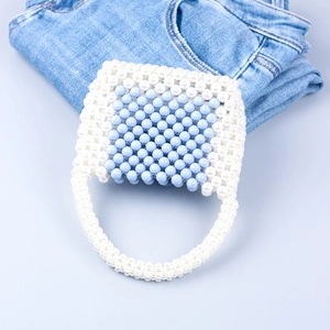 Detailed close-up of handmade white and sky blue woven acrylic beaded handbag with jeans
