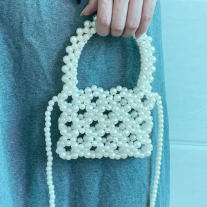 Detail of white handmade pearl beaded square handbag with handle and crossbody strap