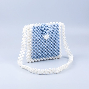 Détail du sac à main perlé bleu et blanc avec fermoir floral et sangle en perles