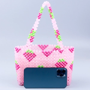 Détail d'un sac à main en perles de fraise roses fait main avec comparatif de taille