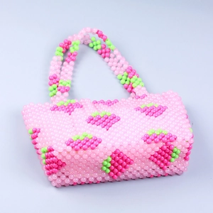 Détail d'un sac à main fait main en perles roses avec un motif de fraise translucide