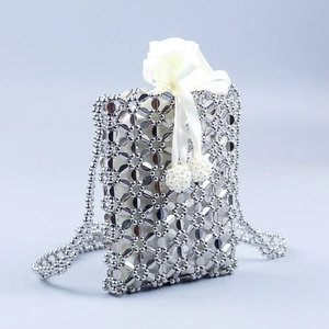 Detail of silver woven crossbody bag with hollow floral pattern and satin drawstring pouch