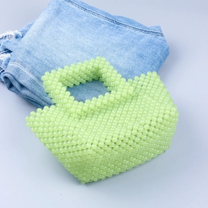 Sac à main artisanal en perles vert menthe sur un jean avec esthétique minimaliste