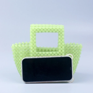 Sac fourre-tout perlé vert menthe fait main avec un smartphone pour comparer la taille