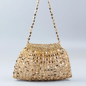 Detailed view of handmade gold metal disc chainmail texture on a stylish bucket bag