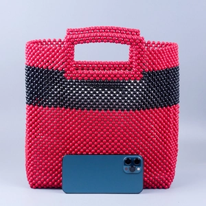 Handmade beaded tote bag in red and black pattern with phone for size comparison