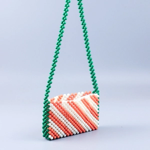 Detailed view of handmade beaded bag with orange, white and green diagonal stripes texture