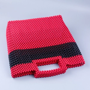 Detail of handmade beaded tote bag featuring red and black acrylic beadwork texture