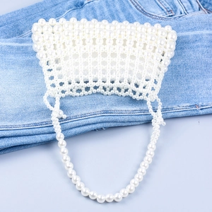 Detailaufnahme der eleganten handgefertigten Perlenhandtasche auf blauem Denim