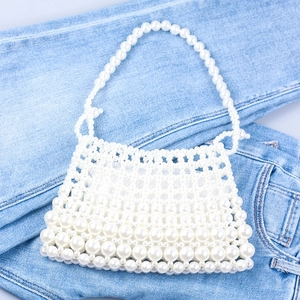 Detail der handgefertigten weißen Perlenhandtasche auf Denim, zeigt elegante Webstruktur