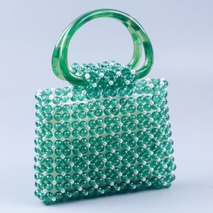 Macro detail of green acrylic beads and white pearls woven into a mesh handbag pattern