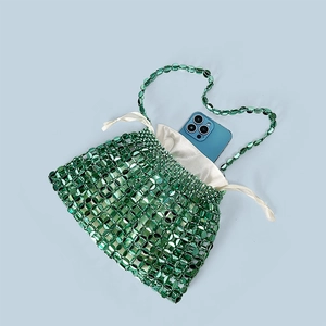 Detail showing green beaded handbag capacity with satin pouch and smartphone for scale
