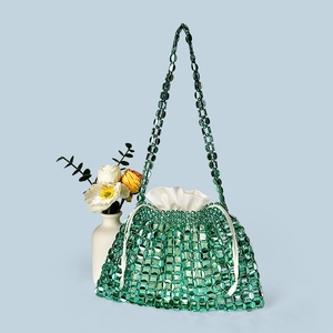Detail of emerald green beaded handbag featuring woven mesh and white satin drawstring pouch