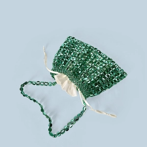Close-up of emerald green beaded handbag featuring woven flat beads and white satin liner
