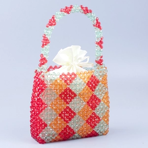 Detail of handmade beaded handbag with red green orange diamond pattern and satin pouch