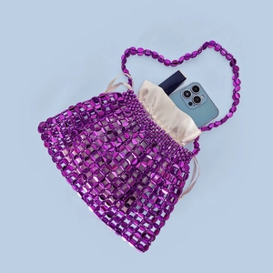 Macro view of purple sequin woven handbag showing white satin drawstring lining and interior