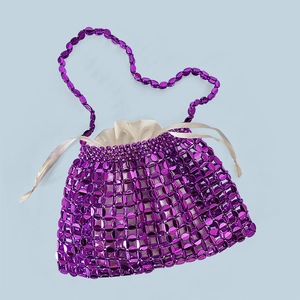 Detail of purple beaded handbag with white satin drawstring bag and long strap