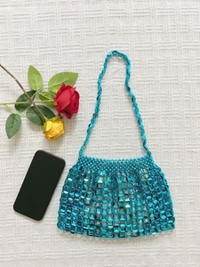 Detailed view of large blue beaded hand-woven dumpling bag with mobile phone for size scale