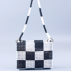 Close-up of handmade checkered beaded bag with polished black and white beads and gold rings