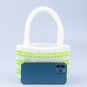 Handmade beaded handbag with green yellow stripes next to phone for size reference