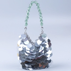 Detailed macro view of silver sequins and green translucent beaded handle on evening bag