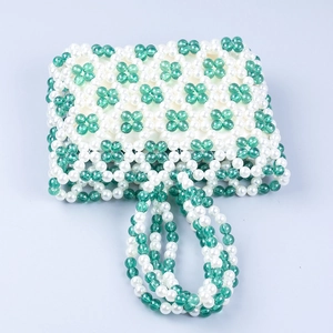 Detail of green and white acrylic beads on a handmade woven hollow-out handbag